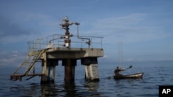 Un pescador navega frente a una perforadora petrolera fuera de operaciones en el lago Maracaibo en Venezuela, a principios del 12 de octubre de 2022. 
