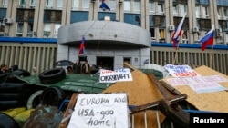 Tulisan-tulisan anti-Barat terlihat di barikade yang dipasang di luar gedung pemerintahan yang diduduki separatis pro-Rusia di Luhansk, Ukraina timur (10/4). (Reuters/Shamil Zhumatov)