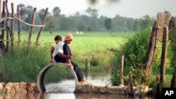 Two Cambodian boys fish on an empty drainage pipe at the natural irrigation canal in Kompong Speu province.