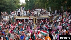 Supporters listen to a speech by Muhammad Tahirul Qadri, Sufi cleric and leader of political party Pakistan Awami Tehreek (PAT), during a demonstration outside his residence in Lahore, August 10, 2014.