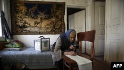 An woman uses a magnifying glass to read her ballot while voting at home in the village of Gornostaypol, some 80 km north of Kiev, on October 26, 2014, during Ukraine's parliamentary elections. Ukrainians voted in parliamentary elections on October 26 th