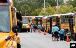 Bus drivers with the Greenville, S.C., school district wait by their buses in the parking lot at the North Charleston Coliseum for word on when to start evacuating people to Greenville from North Charleston, S.C., Oct. 5, 2016, in advance of Hurricane Matthew.