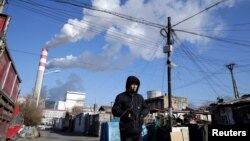 FILE PHOTO: FILE PHOTO: A man walks near a coal-fired power plant in Harbin, Heilongjiang province, China November 27, 2019. Picture taken November 27, 2019. REUTERS/Jason Lee/File Photo/File Photo