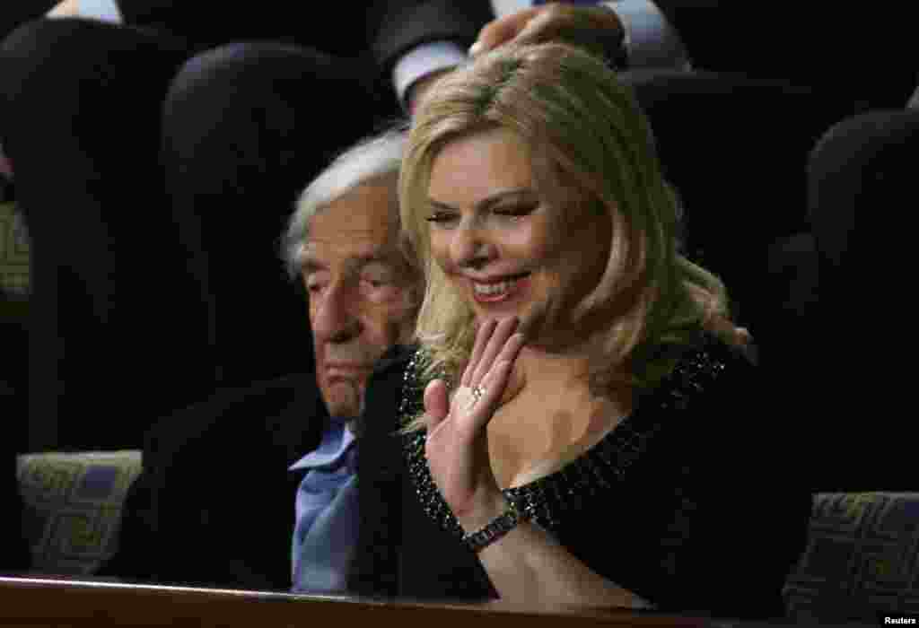 Sara Netanyahu, wife of Israeli Primine Minister Benjamin Netanyahu, waves as she sits next to Holocaust survivor and writer Elie Wiesel in the House Chamber prior to Prime Minister Netanyahu&#39;s address to a joint meeting of Congress in the House Chamber, Capitol Hill, Washington, March 3, 2015.