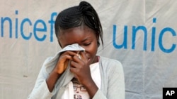 Little 11-year-old German Umba, whose father died in May of Ebola and who is being monitored by the U.N. for potential signs of infection along with her 6-year-old brother, hides her face in her shirt, sobbing, outside her classroom in Mbandaka, Congo.