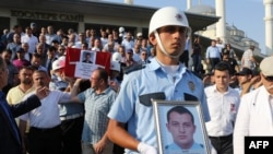 A Turkish Police officer holds a picture of one of the police officers killed during the failed July 15 coup attempt as other police officers carry the coffin during a funeral ceremony in Ankara on July 18, 2016. (AFP PHOTO / ADEM ALTAN)