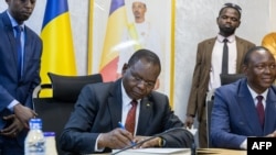 FILE —Chad's former ambassador to China and incoming Chadian Prime Minister Allamaye Halina (L) signs a document during the handover ceremony with outgoing Chadian Prime Minister Succes Masra (R) at the Prime Minister's office in N'Djamena on May 24, 2024.