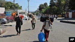 Indian students returning from Uttar Pradesh amid Coronavirus concerns walk after arriving at a railway station in Jammu, India, Sunday, March 22, 2020. India is observing a 14-hour “people's curfew” called by Prime Minister Narendra Modi in order…