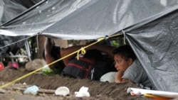 Migrantes de una caravana que avanza por el sur de México se protegen de la lluvia bajo una carpa en Mapastepec, en el estado de Chiapas, el 31 de octubre de 2021.