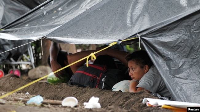 Migrantes de una caravana que avanza por el sur de México se protegen de la lluvia bajo una carpa en Mapastepec, en el estado de Chiapas, el 31 de octubre de 2021.