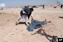 An Afghan man looks at the dead body of a victim of suicide attack in Lashkar Gah the capital of southern Helmand province, Oct. 10, 2016.