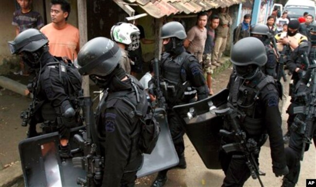 Para anggota Densus 88 membawa perlengkapan dan senjata mereka setelah melakukan penggerebekan di rumah yang ditempati oleh militan di Kabupaten Bandung. (Foto: AP)