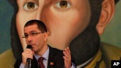 El canciller venezolano Jorge Arreaza habla durante una reunión con diplomáticos, con el retrato de Simón Bolívar como fondo.