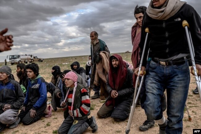 Men and boys suspected of being Islamic State (IS) fighters wait to be searched by members of the Kurdish-led Syrian Democratic Forces (SDF) after leaving the IS group's last holdout of Baghouz, in Syria's northern Deir Ezzor province, Feb. 27, 2019.