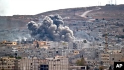 Smoke rises above the Syrian town of Kobani after an airstrike by the U.S.-led coalition, seen from a hilltop on the outskirts of Suruc, Turkey, near the Turkey-Syria border, Oct. 26, 2014. 