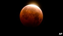 FILE - Light shines from a total lunar eclipse over Santa Monica Beach in Santa Monica, Calif., Wednesday, May 26, 2021. (AP Photo/Ringo H.W. Chiu)
