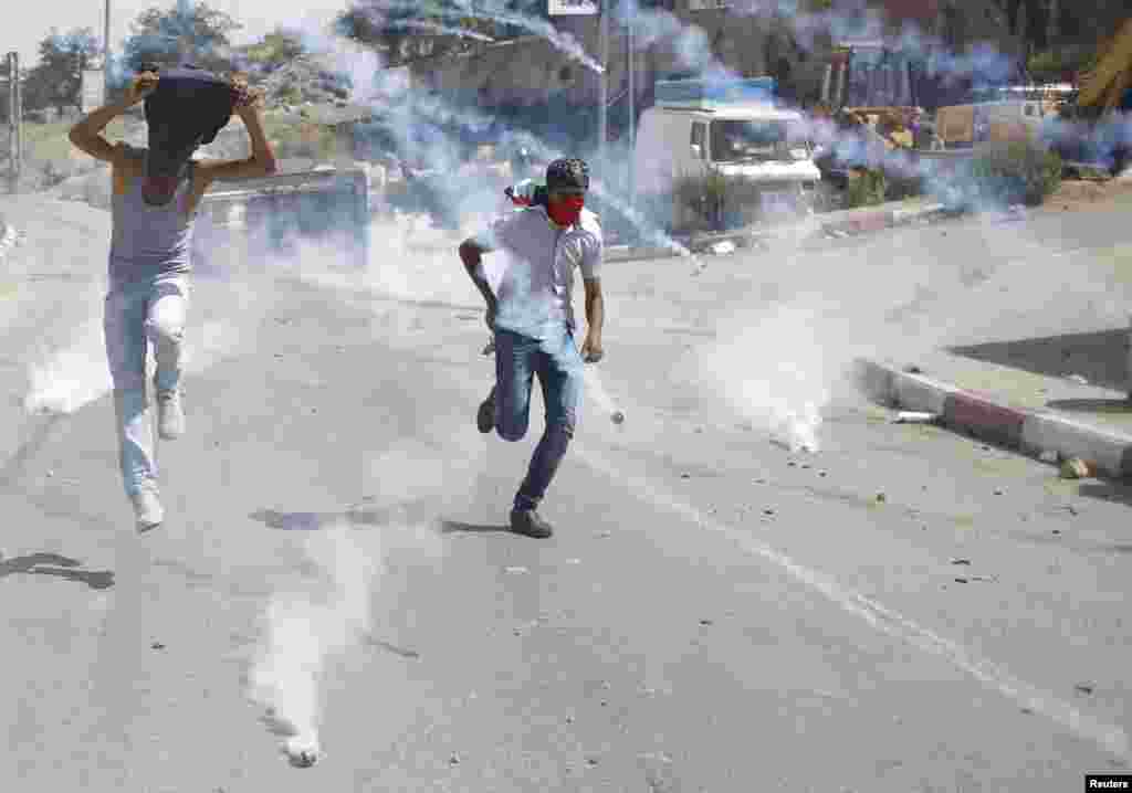 Palestinian protesters run from tear gas fired by Israeli troops during clashes near Israel's Ofer Prison, near the West Bank city of Ramallah.