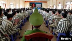 FILE - Policemen (center row) keep watch as inmates wait before being released from Hoang Tien prison, about 100 km (62 miles) outside Hanoi.