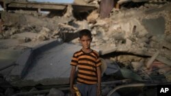 In this July 13, 2017 photo, Ali Mahdi, 9, poses for a photo while playing on his damaged street on the west side of Mosul, Iraq.