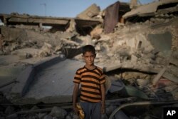 FILE - In this July 13, 2017, photo, Ali Mahdi, 9, poses for a photo while playing on his damaged street on the west side of Mosul, Iraq.
