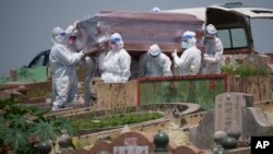 Health workers wearing Personal Protective Equipment (PPE) carry a coffin during a funeral for a COVID-19 victim in Klang, Malaysia, Sunday, May 23, 2021. 