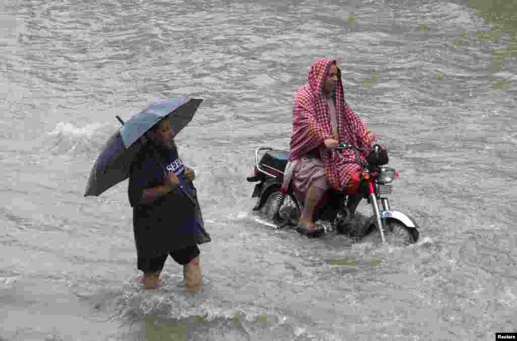 لاہور میں ماہ اگست کا پہلا دن بھی بارشوں کی نذر ہوا جبکہ پچھلے ہفتے کی بارش کے دوران ایک شخص چھتری لیے اپنی منزل کی جانب گامزن ہے جبکہ دوسرا شخص موٹر سائیکل پر سوار ہے۔ &nbsp;