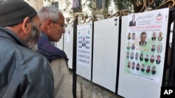 Des passants regardent les affiches de campagne électorale pour les prochaines élections législatives à Alger, Algérie, 9 avril 2017.