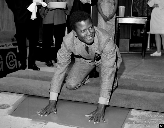 FILE - Sidney Poitier, star of "To Sir With Love," places his hands in wet cement at Grauman's Chinese Theater in Los Angeles on June 23, 1967. (AP Photo/File)