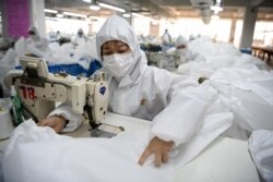 FILE - Workers sew hazardous material suits to be used in the COVID-19 outbreak at the Zhejiang Ugly Duck Industry garment factory in Wenzhou, China.