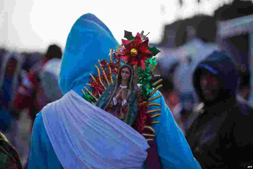 A pilgrim carries a statuette of the Virgin of Guadalupe on his back during the annual celebrations at the Basilica of Guadalupe in Mexico City.