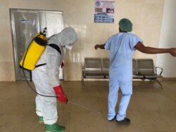 FILE - A health worker wearing protective equipment disinfects a member of medical staff amid the spread of the coronavirus disease (COVID-19), at an hospital in Douala, Cameroon, April 27, 2020.