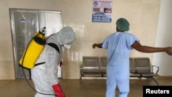 A health worker wearing protective equipment, disinfects a member of medical staff amid the spread of the coronavirus disease (COVID-19), at an hospital in Douala, Cameroon, April 27, 2020.