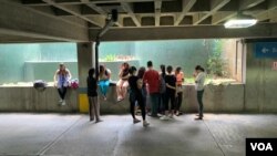 Venezolanos esperan su turno para cargar sus móviles en el estacionamiento de una farmacia, mientras cumplen un día sin luz en Caracas.