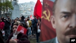 Communist Party supporters stand next to a monument to Karl Marx, left, and hold Soviet flags and portraits of Soviet founder Vladimir Lenin, right, during a demonstration marking the 100th anniversary of the 1917 Bolshevik Revolution in Moscow, Russia, Nov. 7, 2017.