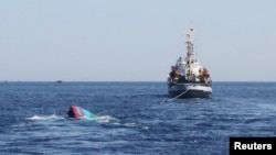 FILE - A sinking Vietnamese boat, left, which was rammed and sunk by Chinese vessels near disputed Paracels Islands, is seen near a Marine Guard ship, right, at Ly Son island of Vietnam's central Quang Ngai province May 29, 2014.