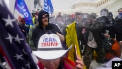 En esta fotografía de archivo del 6 de enero de 2021, insurrecciones leales al presidente Donald Trump intentan atravesar una barrera policial en el Capitolio en Washington.