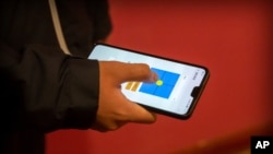 FILE - A person uses a smartphone app in an illustration photo taken March 18, 2020. South African organization Praekelt.org has gone global with a Whatsapp bot that raises awareness about the coronavirus.