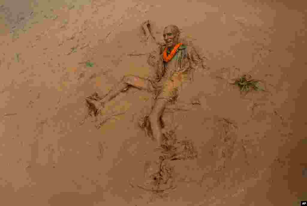 An elderly man falls in the mud in a paddy field during &#39;Asar Pandra&#39;, or paddy plantation day in Dhading district, Nepal.