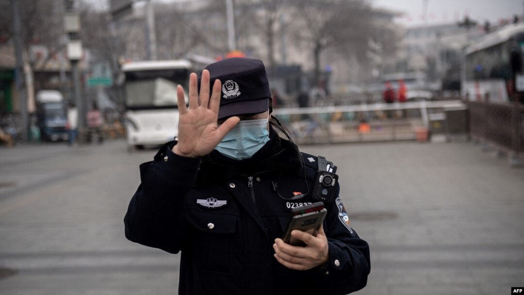 FILE - A police officer gestures during the opening session of the National Peoples Congress in Beijing, March 5, 2021.