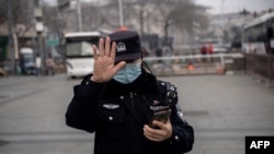 FILE - A police officer gestures during the opening session of the National Peoples Congress in Beijing, March 5, 2021.