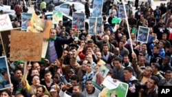 Libyan pro-government supporters hold portraits of leader Moammar Gadhafi during a gathering in Tripoli, February 16, 2011