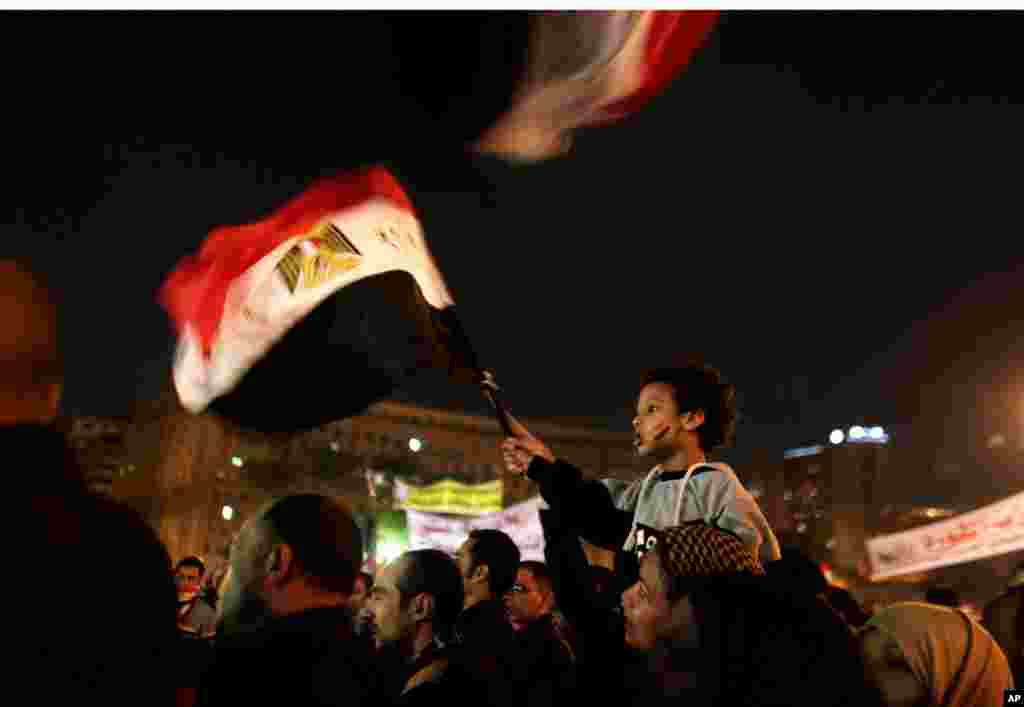 A young boy waves a national flag from his mother's shoulders as protesters chant slogans in Tahrir Square in Cairo, Egypt, December 4, 2012.