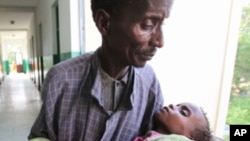 這名索馬里男子抱著他營養不良的孩子在首都摩加迪沙的一家醫院的走廊裡來回走動(資料圖片)