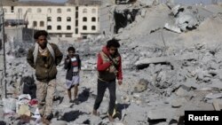 People walk on the rubble of a house destroyed by a Saudi-led airstrike in Yemen's capital, Sanaa, Jan. 29, 2016. 