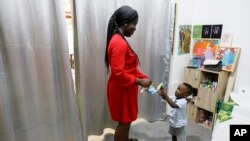 FILE — Chantelle Kuukua Eghan, 25, gives paint to her son Ace-Liam Nana Sam Ankrah, who will turn two in July, at her mother's art gallery in Accra, Ghana, May 27, 2024.