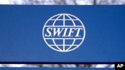 FILE - A sign for the Society for Worldwide Interbank Financial Telecommunications ( SWIFT) is seen outside the company headquarters in Brussels, Feb. 20, 2007.