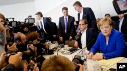 German Chancellor Angela Merkel, chairwoman of the Christian Democratic Union, CDU, sits next to CSU's Alexander Dobrindt, second from right, the deputy of the joint CDU/CSU faction in the German parliament prior to a faction meeting, July 2, 2018.