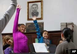 FILE - Dulce Carvajal, 10, second from left, and her sister Daniela, 8, raise their hands during voice lessons at the Holyrood Episcopal Church in the Bronx borough of New York, Oct. 26, 2017. Since August, the girls and their brother have been living inside the church with their mother, a Guatemalan immigrant living illegally in the United States.