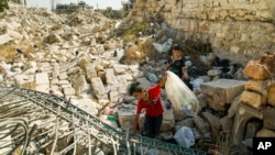 Young boys collect cans in ruins in Aleppo, Syria, Sept. 12, 2017. 