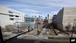 FILE - Normally bustling with folks heading to the city jail or courthouse, two people walk along the path between the two judicial complexes as the fear of coronavirus forces workers to stay home, in Denver, March 16, 2020.